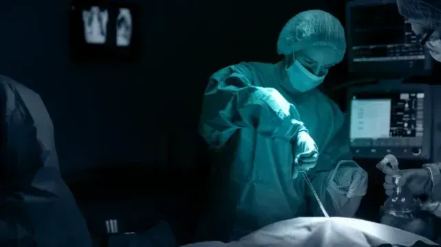 Um cirurgião está operando um paciente em um quarto escuro.