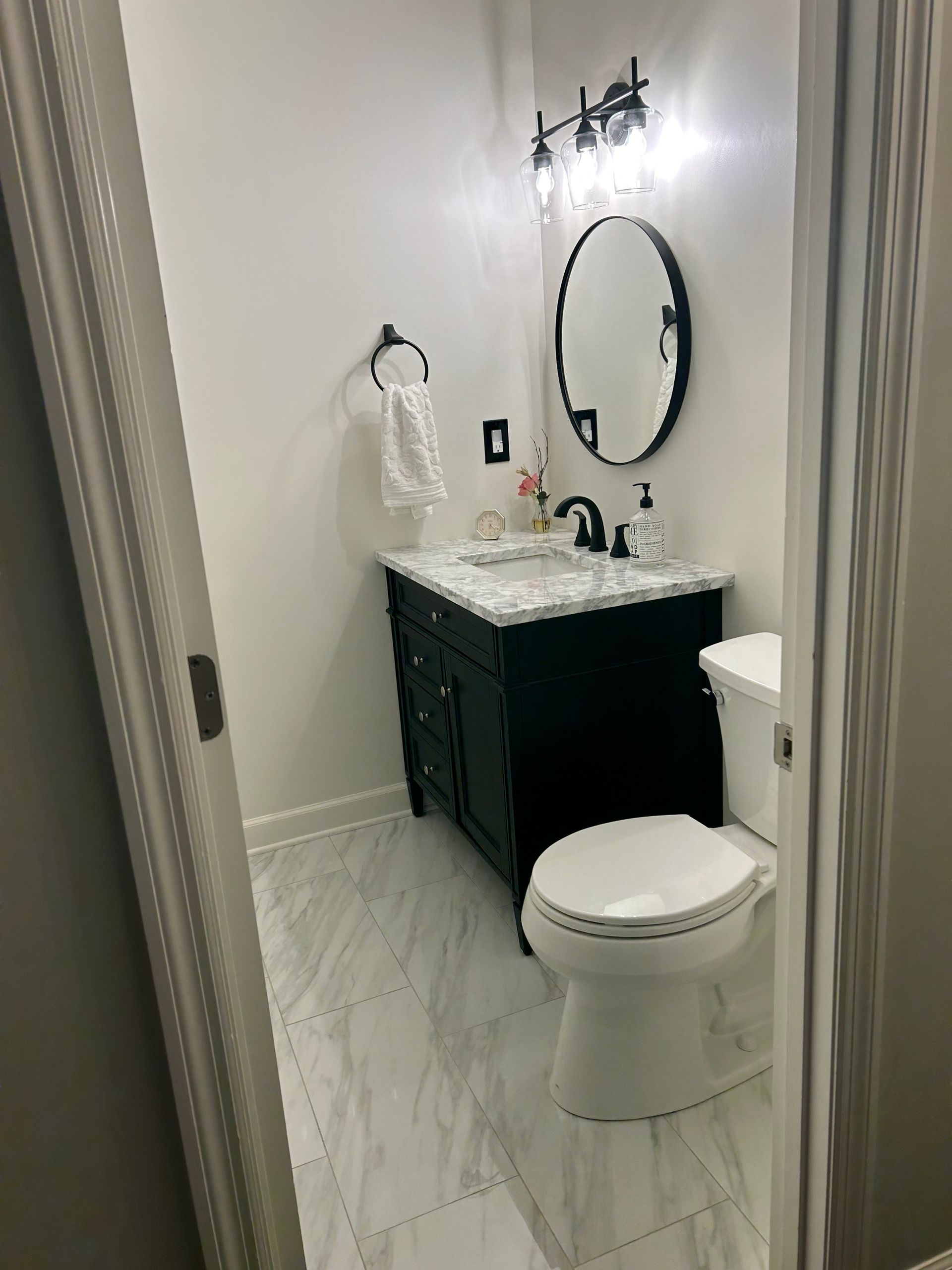 Elegant bathroom vanity with white cabinets, marble countertop, dual mirrors, and wall sconces