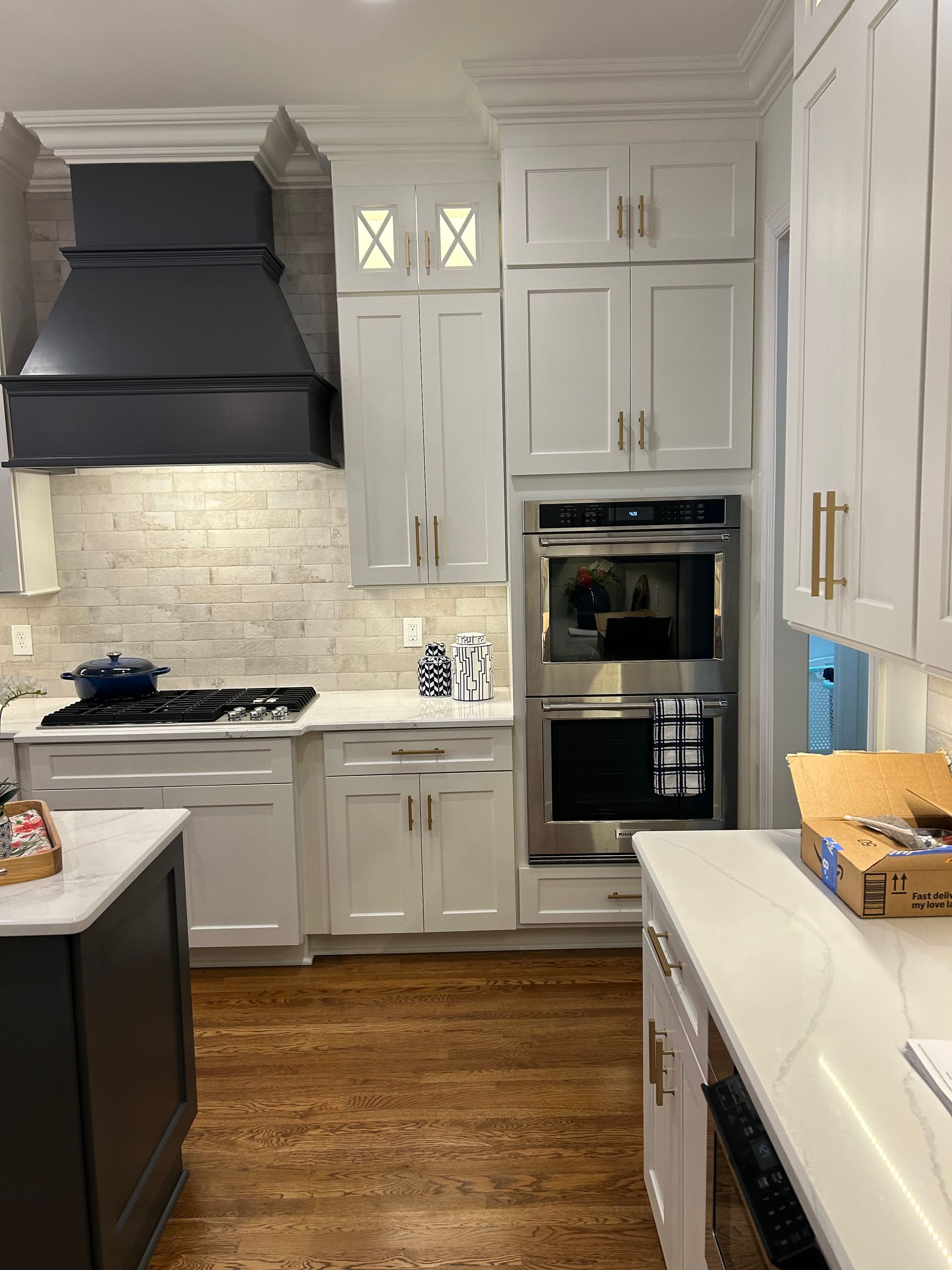 Modern gray kitchen with marble island, stainless appliances, pendant lights, and whitewashed wood floors.