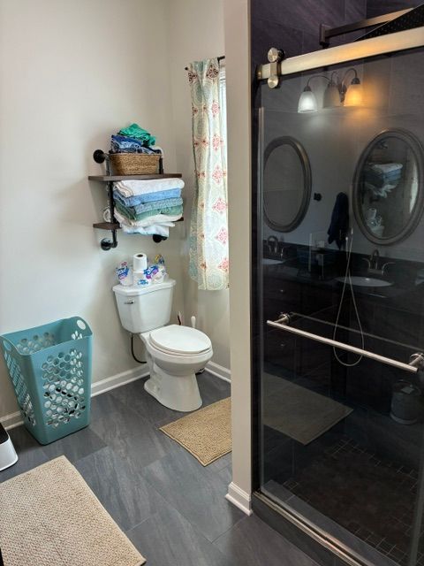 Double vanity bathroom with white cabinets, large mirrors, and gray walls in a bright, modern interior