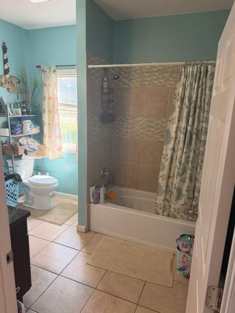 Blue floral bathroom with a corner tub, red flowers, and a vanity with mirror in an adjoining room