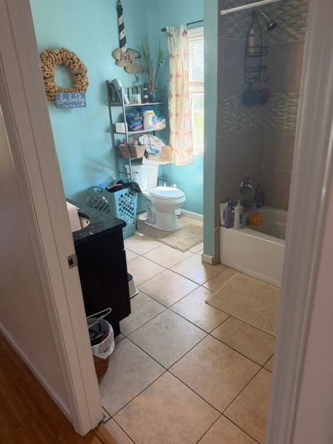 Blue floral bathroom with a corner tub, red flowers, and a vanity with mirror in an adjoining room
