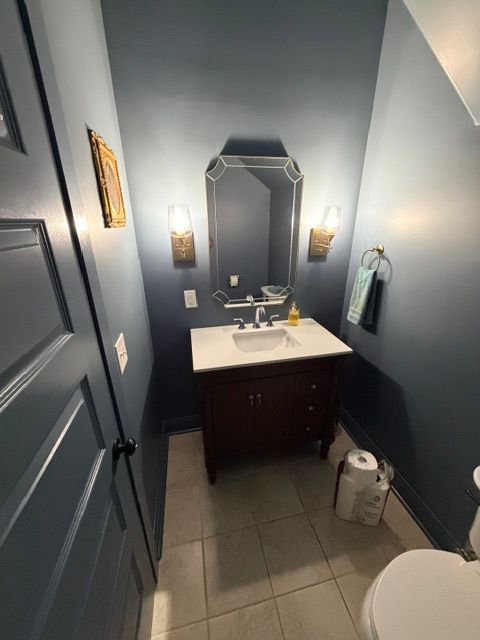 Double vanity bathroom with white cabinets, large mirrors, and gray walls in a bright, modern interior