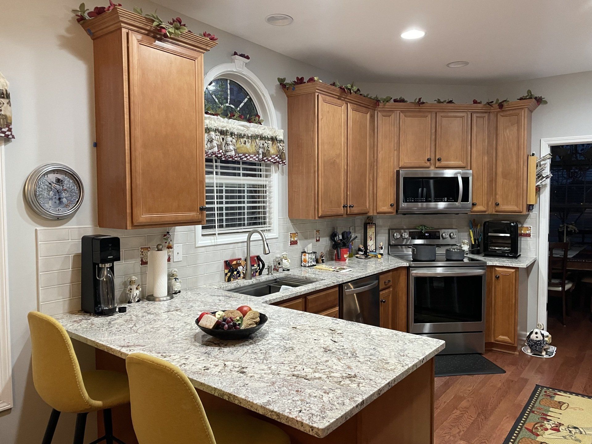 Bright kitchen with wood cabinets, granite island, stainless appliances, and a window above the sink