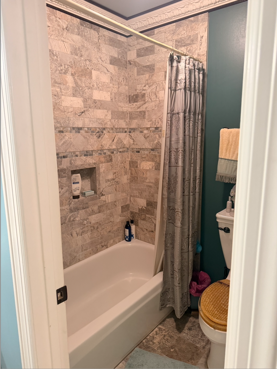 Blue floral bathroom with a corner tub, red flowers, and a vanity with mirror in an adjoining room