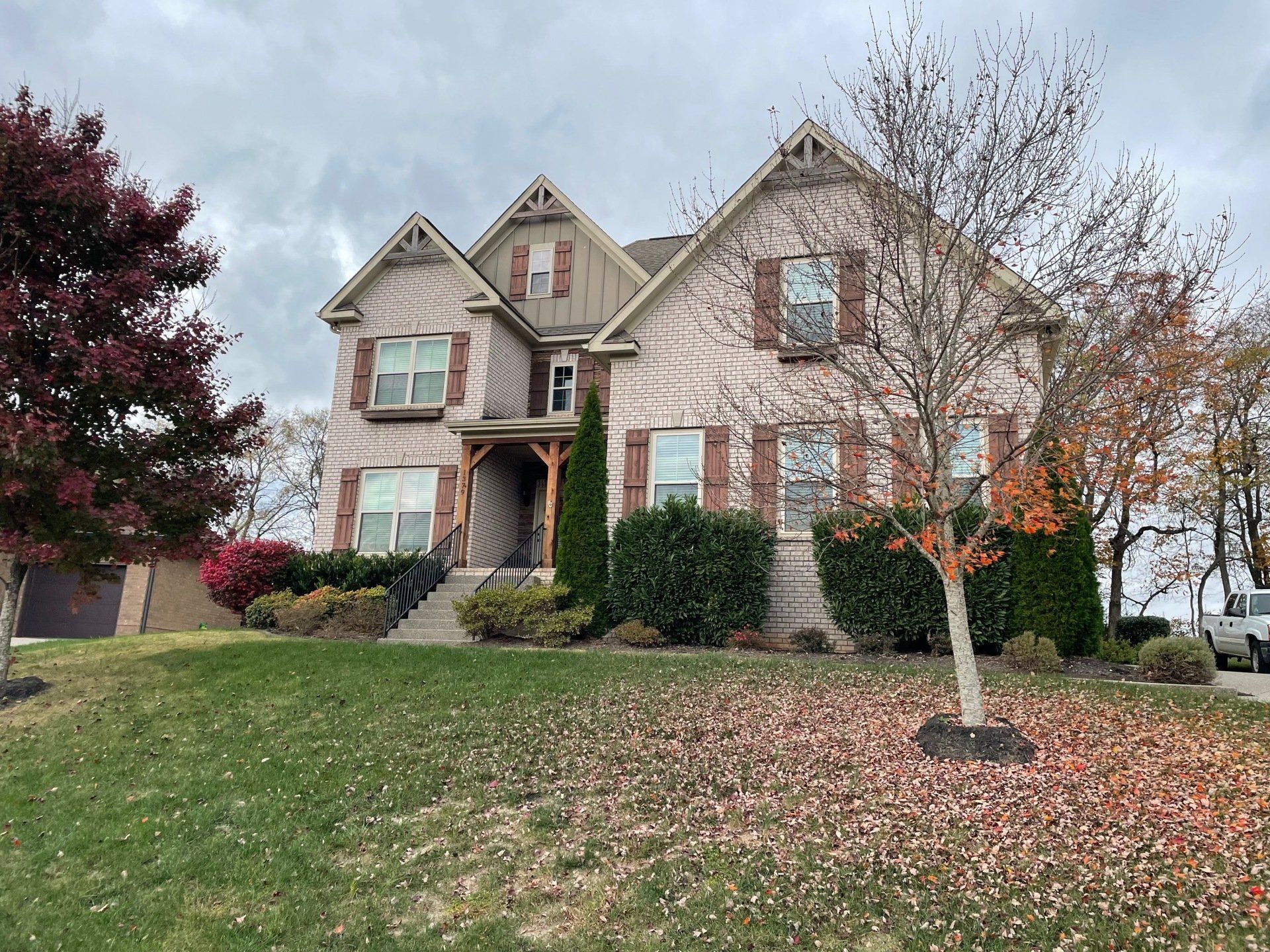 Two-story brick house with fall foliage and a front yard covered in leaves