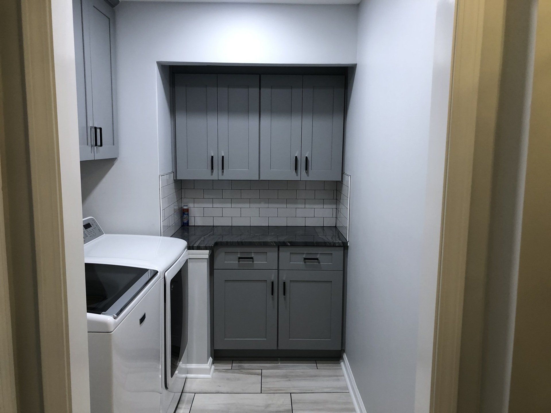 Small narrow kitchen with gray cabinets, white walls, and a stove on the left.