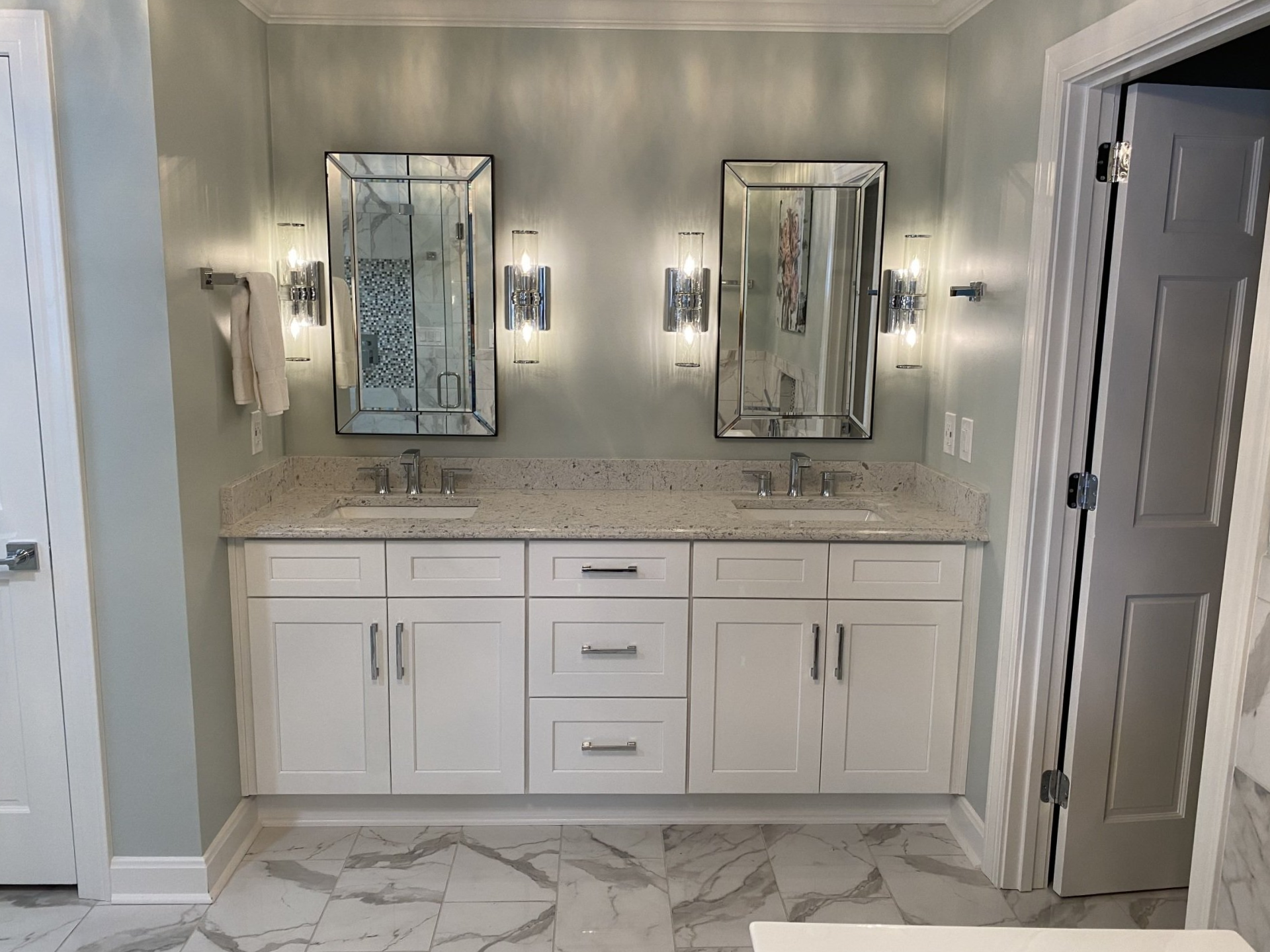 Modern bathroom vanity with twin mirrors, gray walls, and white cabinets with marble countertop.