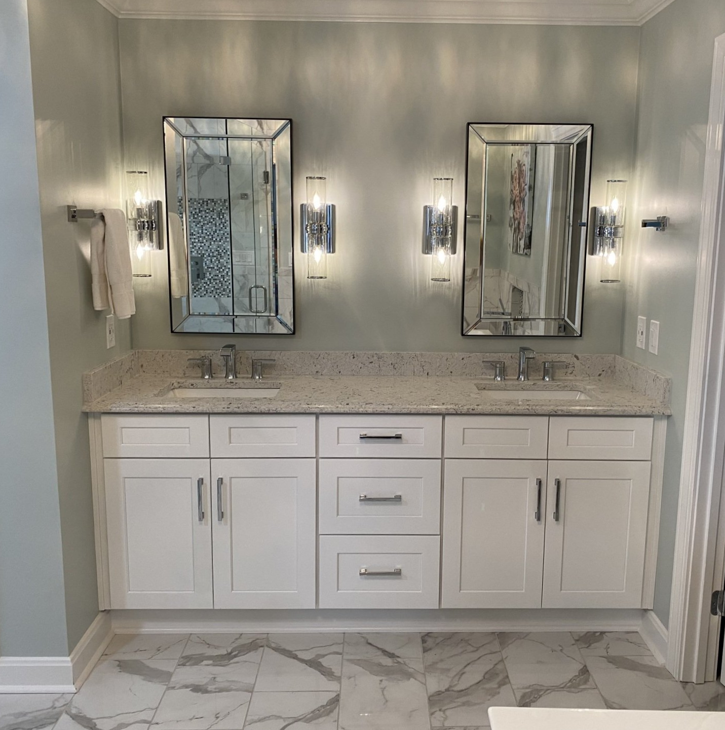 Double vanity bathroom with white cabinets, large mirrors, and gray walls in a bright, modern interior