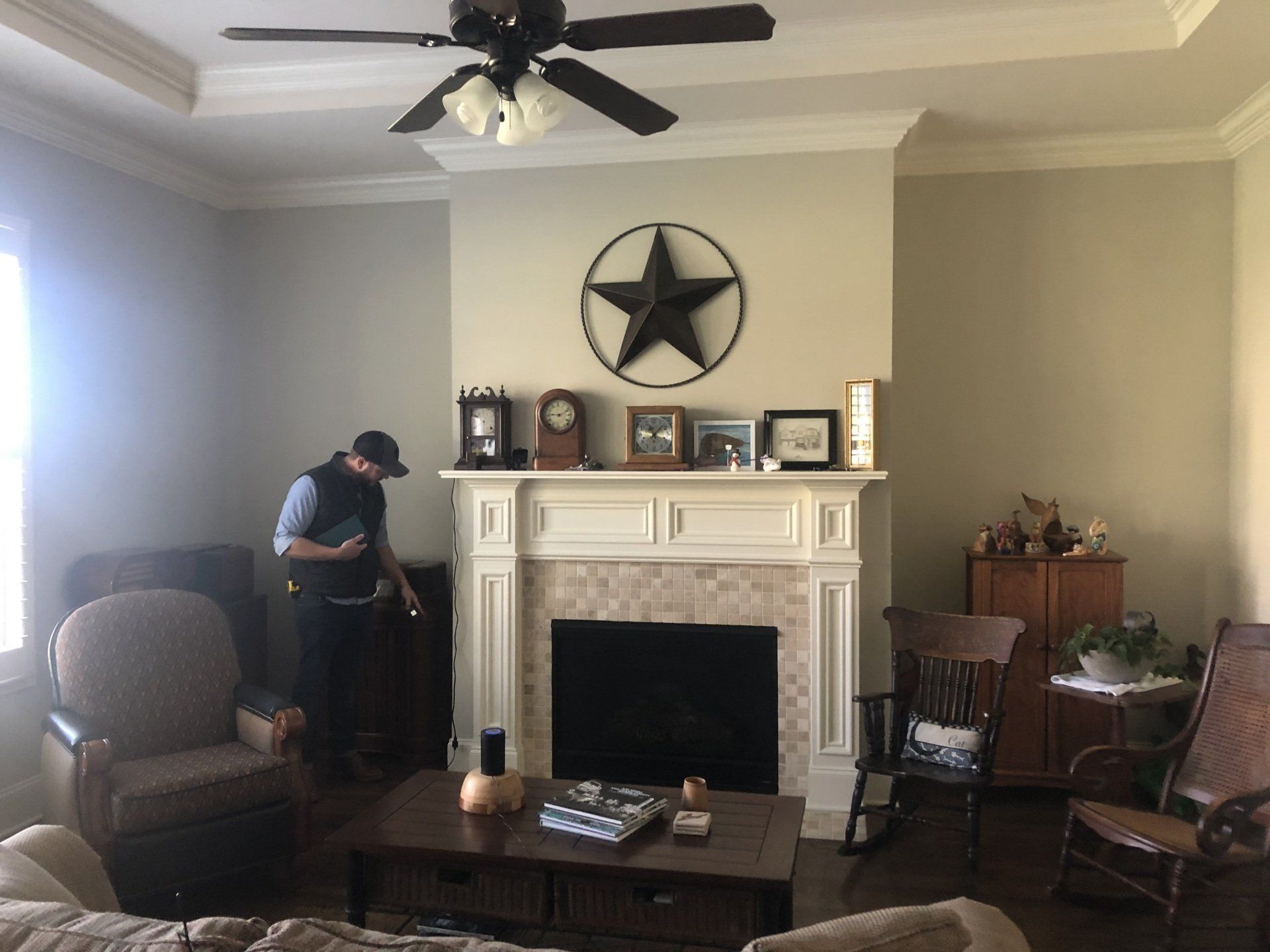 Living room with fireplace and wall star decor; a person bends over near the mantel.