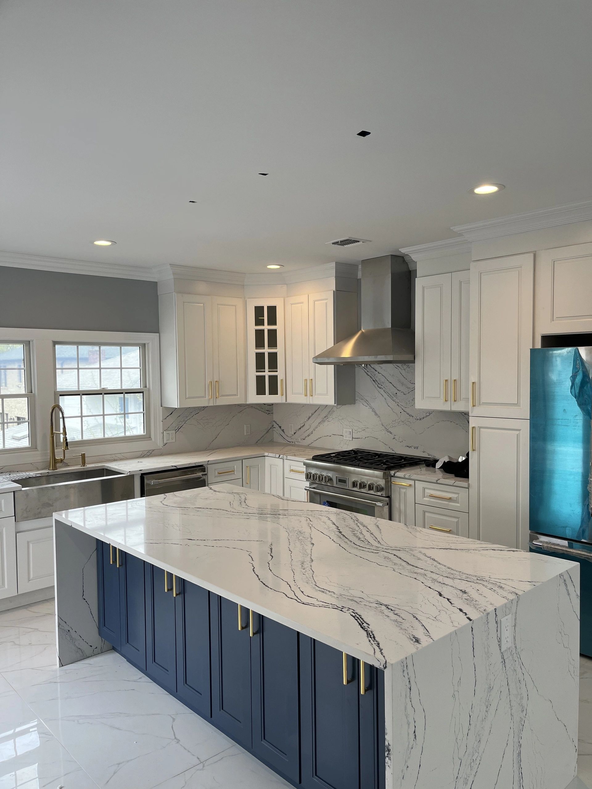 A kitchen with blue cabinets and white counter tops
