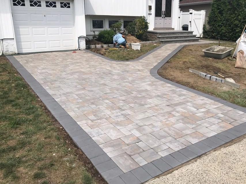 A brick driveway is being built in front of a house.