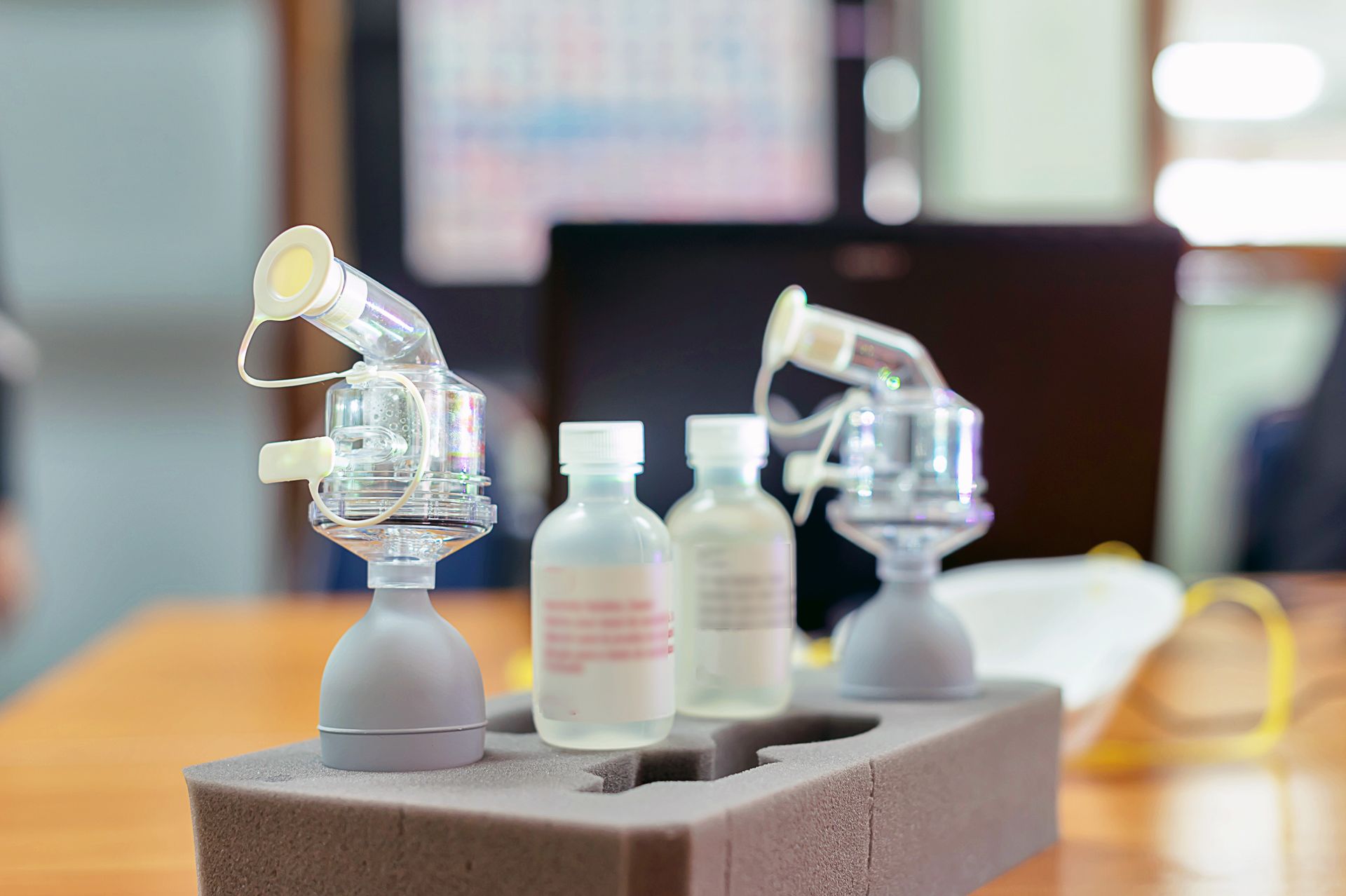 Two clear nebulizer masks on a foam block beside two medicine bottles on a table