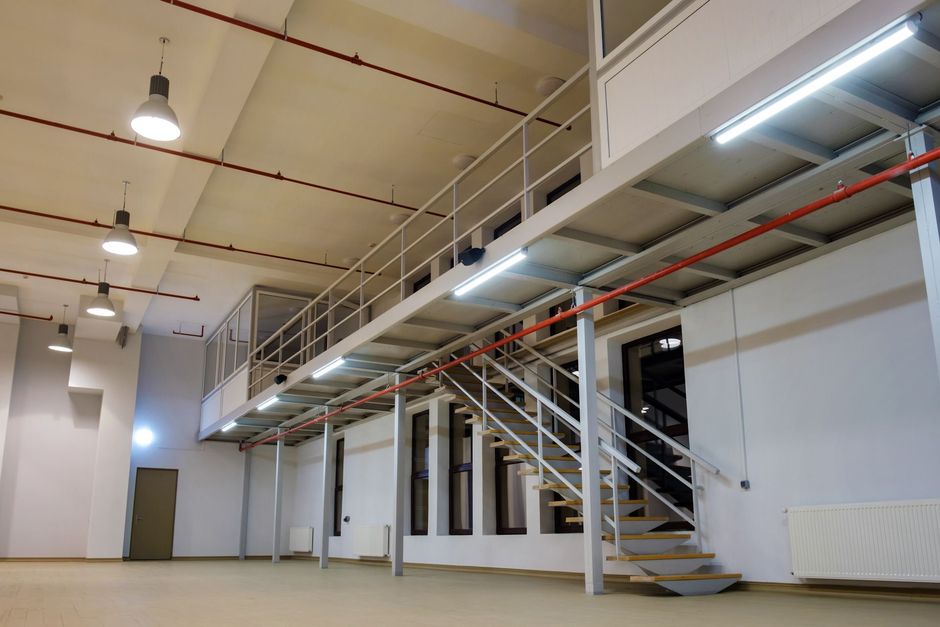 A large empty room with stairs leading up to a second floor.