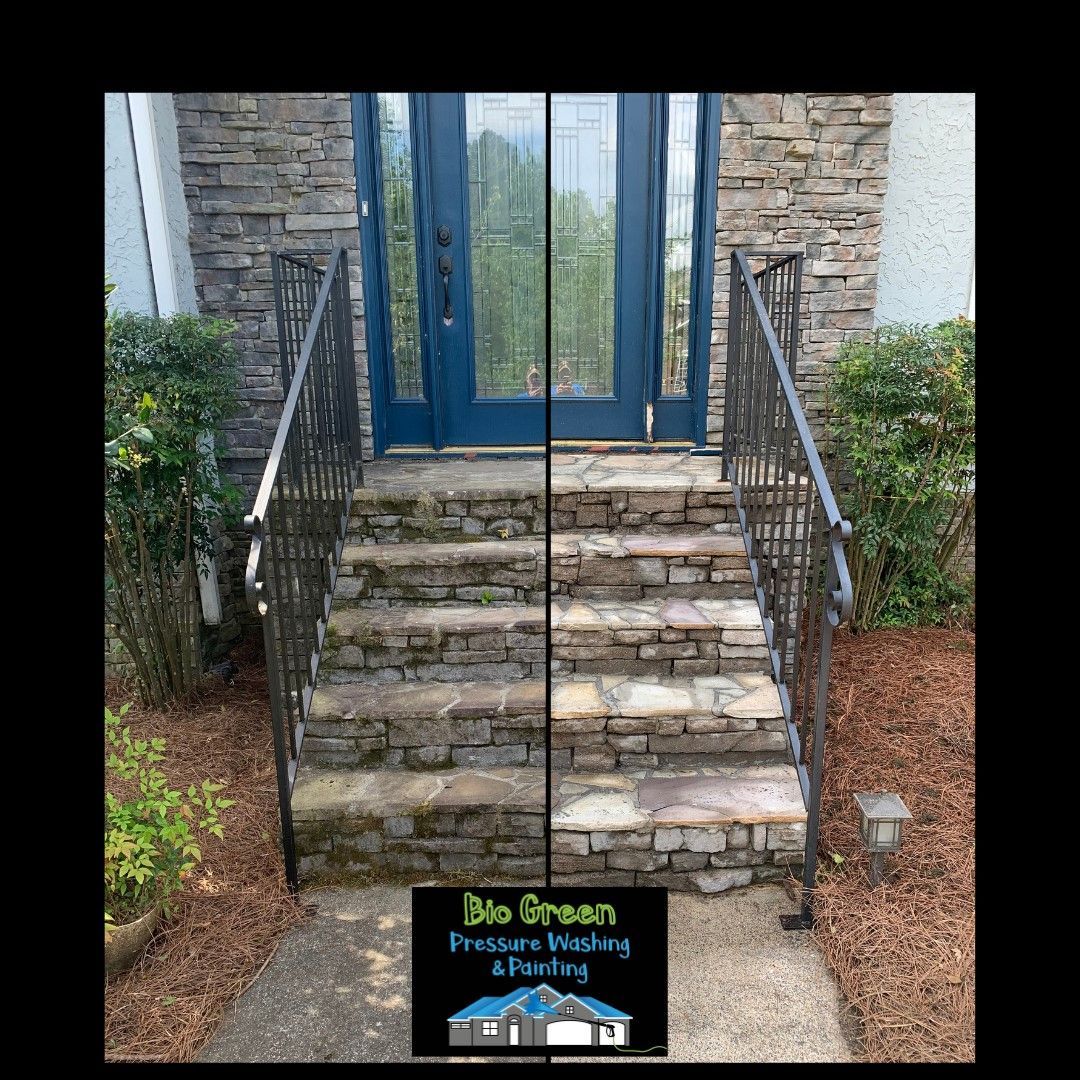 Stone front steps with black railings leading to a blue door, with a small sign at the base.