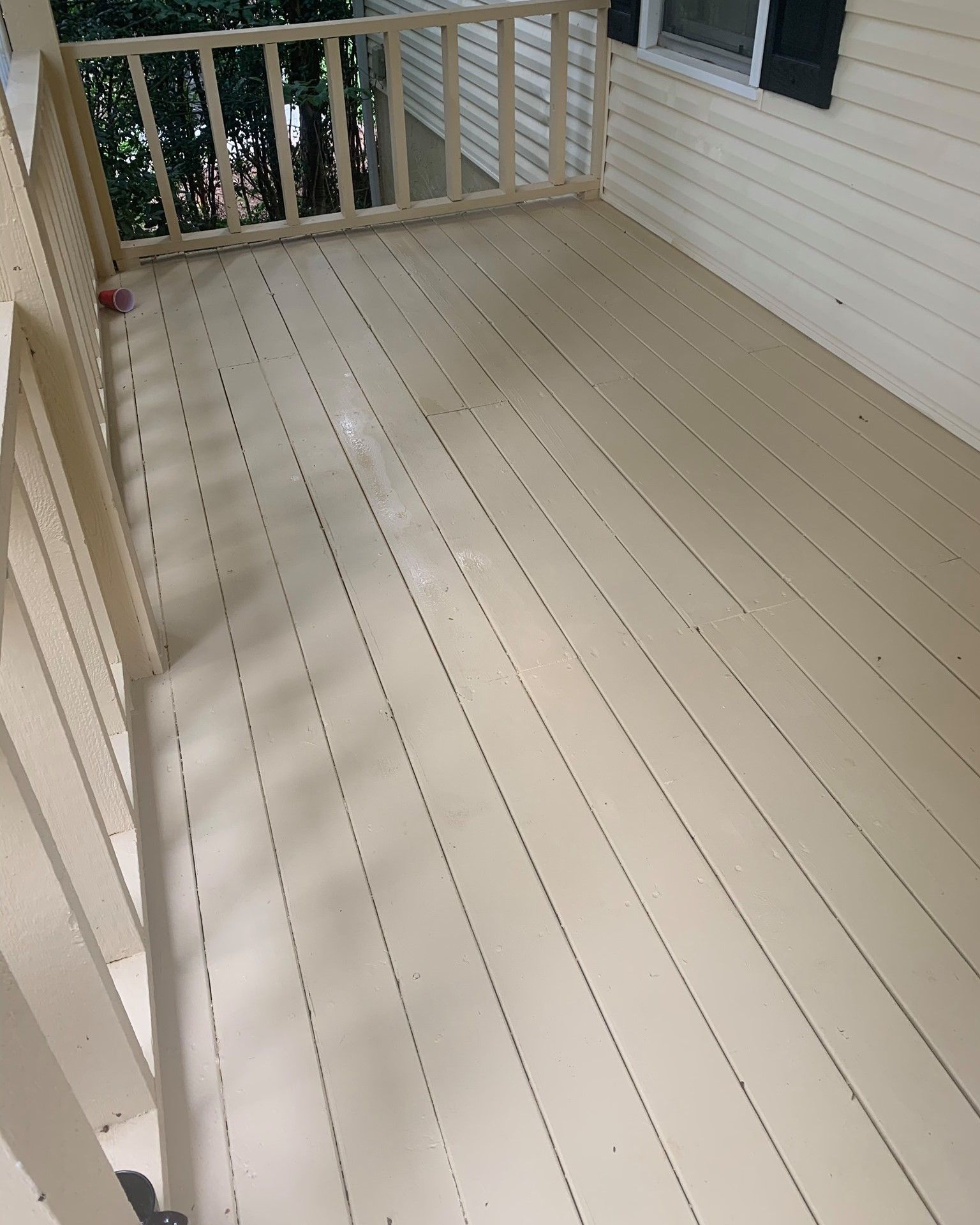 Empty beige-painted wooden porch with railing and siding walls