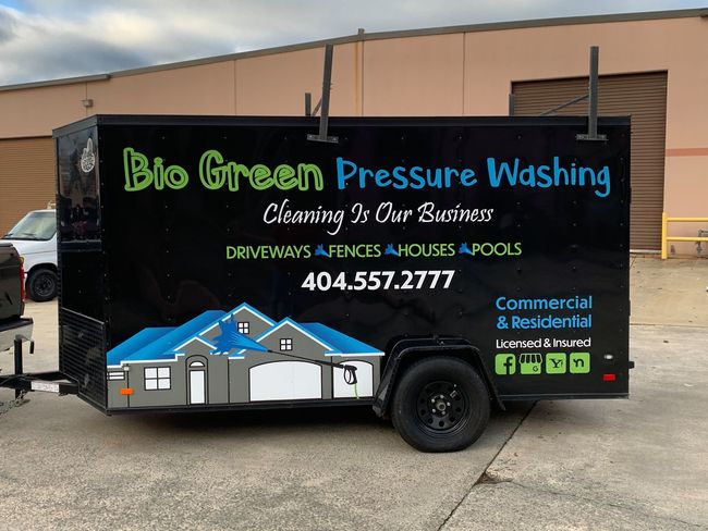 Big Green Pressure Washing trailer with logo and contact info parked outdoors