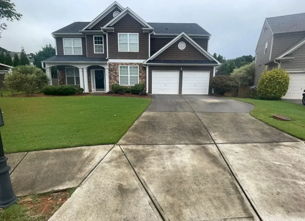 Two-story suburban house with a double garage and wet driveway after rain