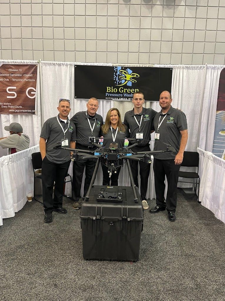 Five people posing at a trade show booth behind a display table with a black equipment case.