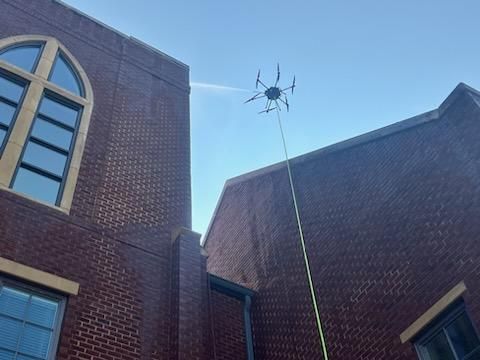 Brick buildings with a drone hovering above them against a blue sky.