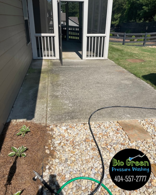 Concrete porch walkway with landscaped edging and a screened entry, partly bordered by mulch and stones.