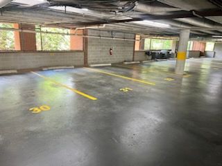 Empty indoor parking garage with numbered spaces and yellow lane markings on a concrete floor.