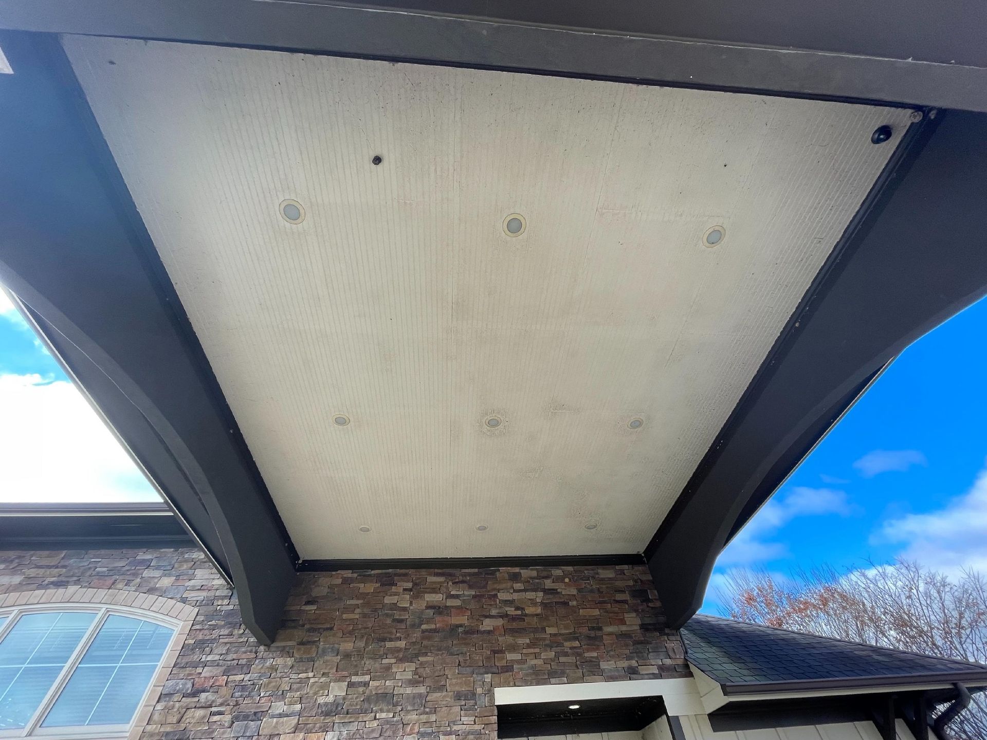 Stone house exterior under a peaked porch ceiling against a bright blue sky