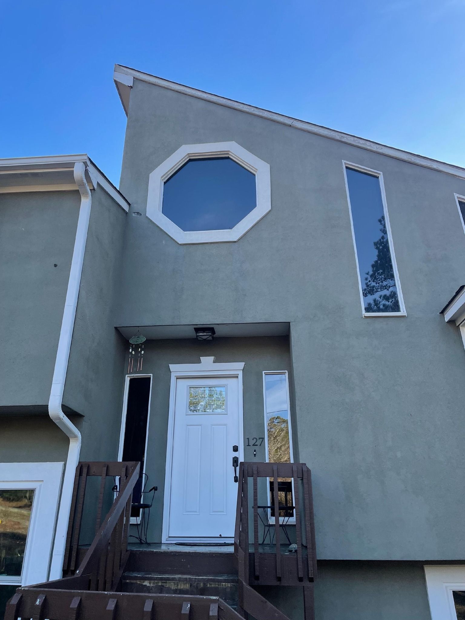 Gray house entrance with white door, small porch, and octagonal window above the entry.