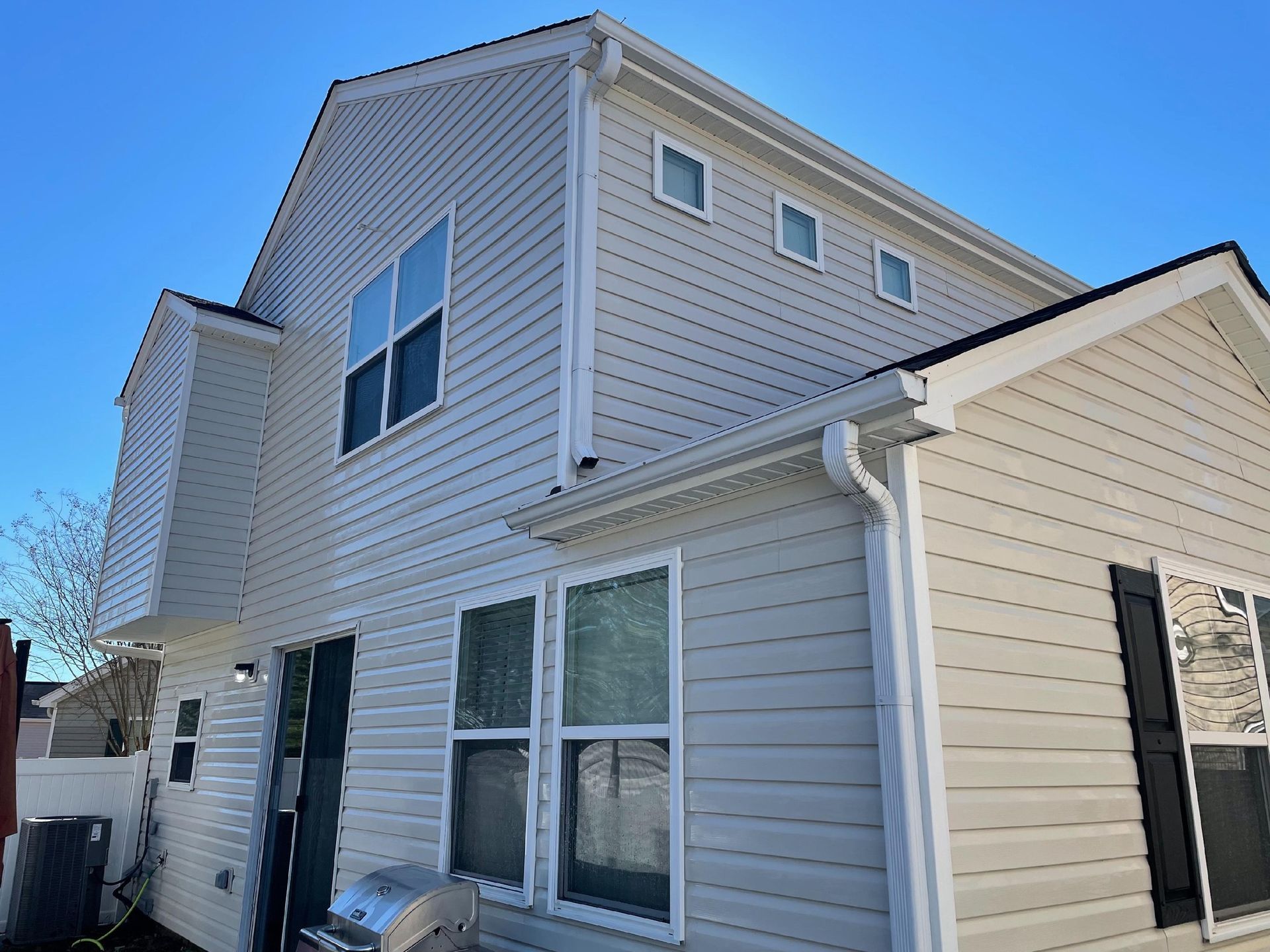 Two-story beige house exterior with white trim and blue sky