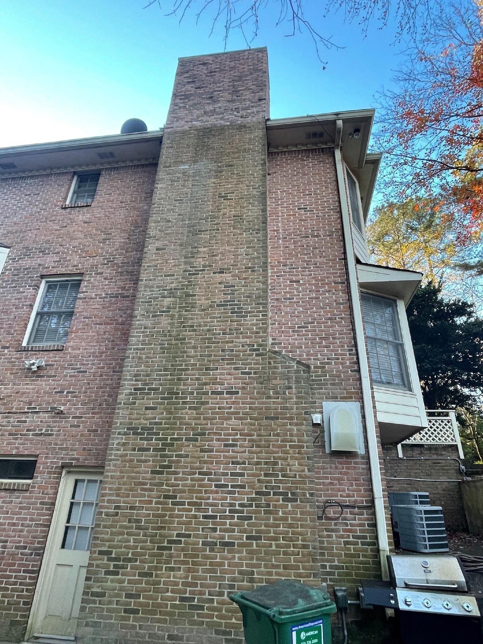 Brick chimney on the side of a brick house against a blue sky