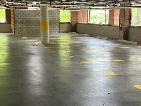 Empty concrete parking garage with yellow lane markings and brick walls.