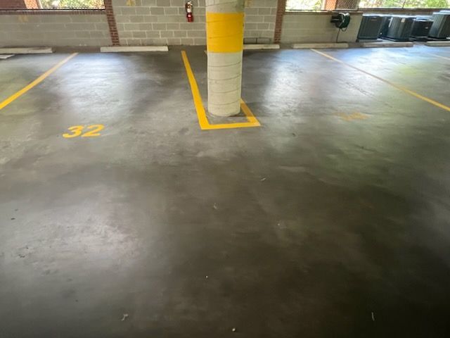 Empty parking garage space marked 32 beside a yellow-striped pillar.