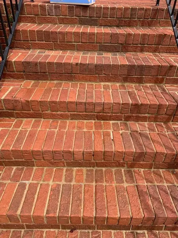 Brick outdoor steps with a central raised strip and worn red treads.