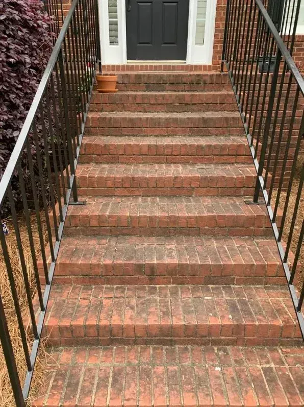 Brick stairway leading to a white front door, with black railings on both sides.