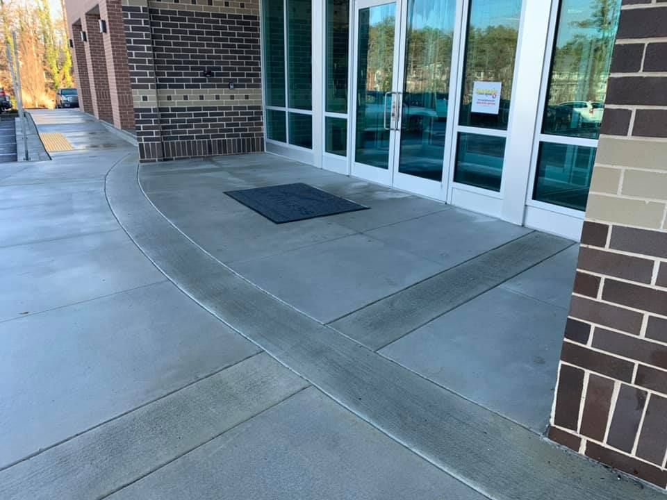 Building entrance with glass doors, concrete walkway, and brick exterior walls