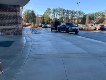 Sidewalk outside a brick building with parked cars and trees in the background