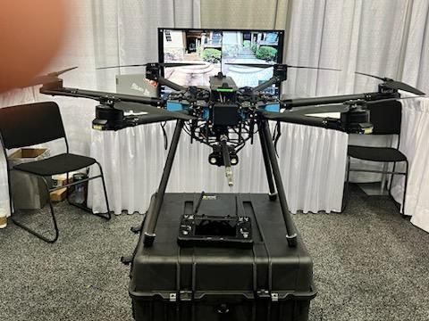 Large drone with camera mounted on a wheeled case in a room with chairs and a TV screen.