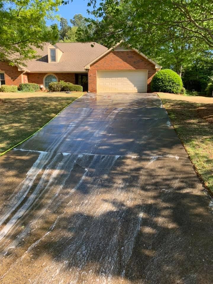 Suburban house with a long driveway, partially washed with wet streaks in sunlight