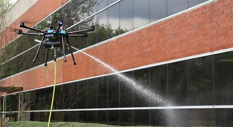 Drone spraying water on a brick office building with reflective windows
