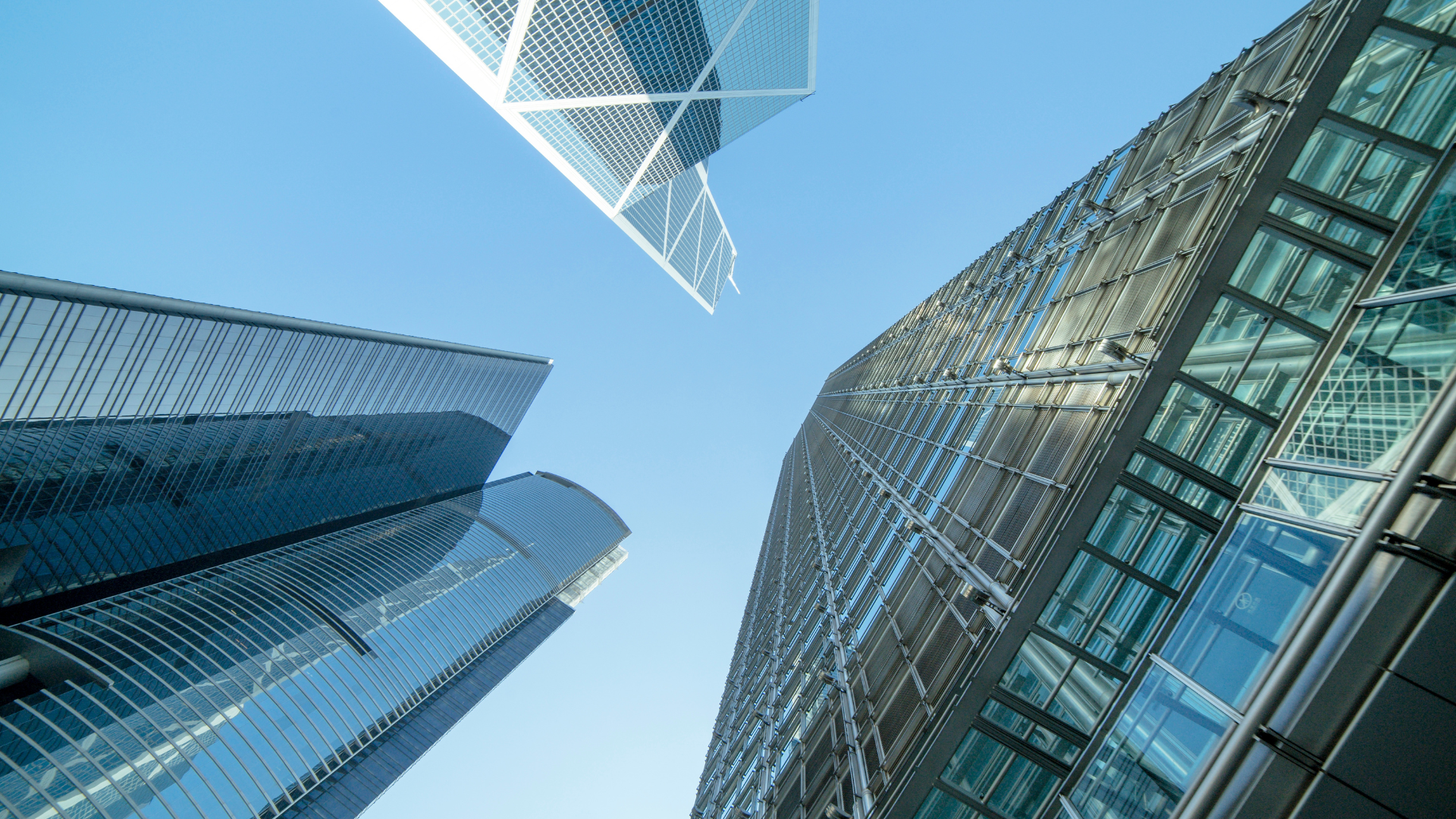 Upward view of modern glass skyscrapers against a blue sky