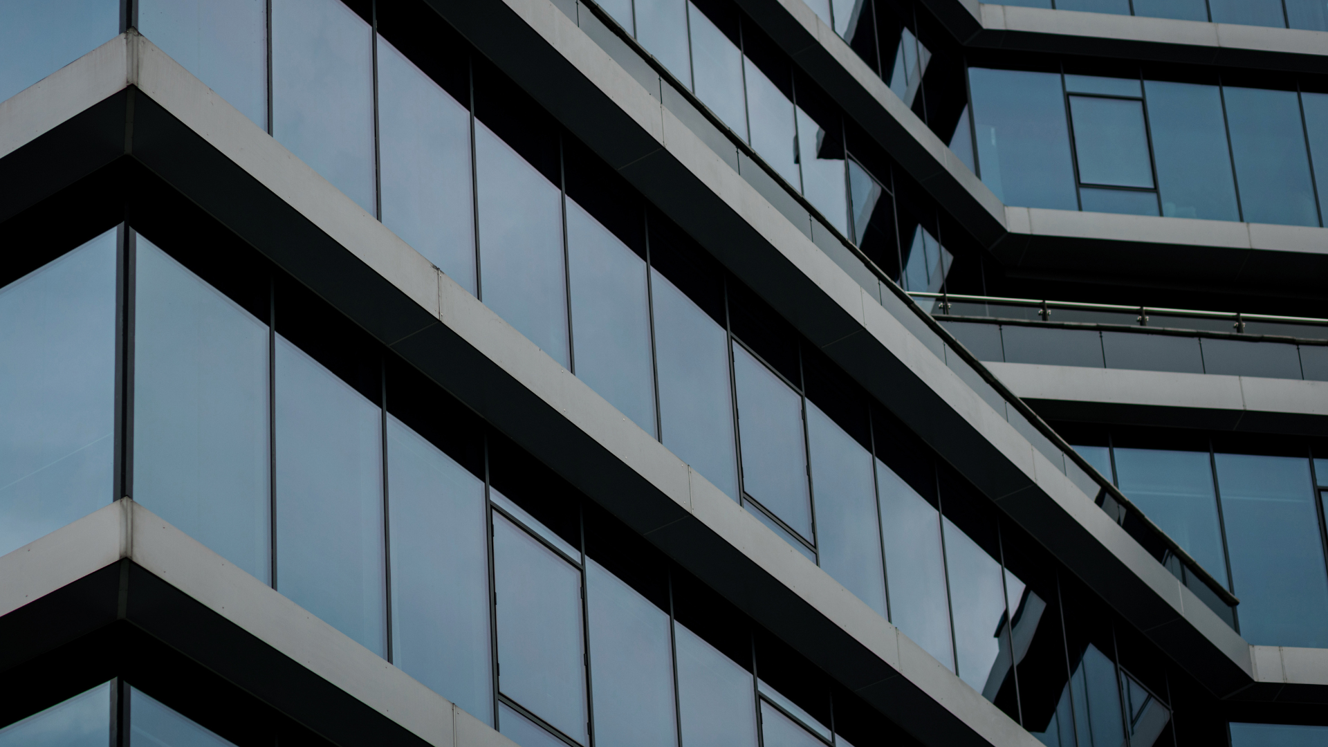 Modern glass office building facade with angular black framing and blue-tinted windows