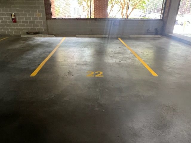 Empty indoor parking space marked 22 with yellow lines and concrete floor