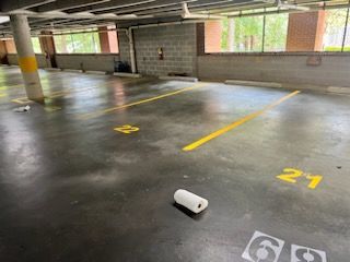 Empty parking garage with a white bottle on the floor near a marked parking space.