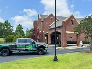 Brick building entrance with a green-and-black pickup truck parked in front on a sunny day