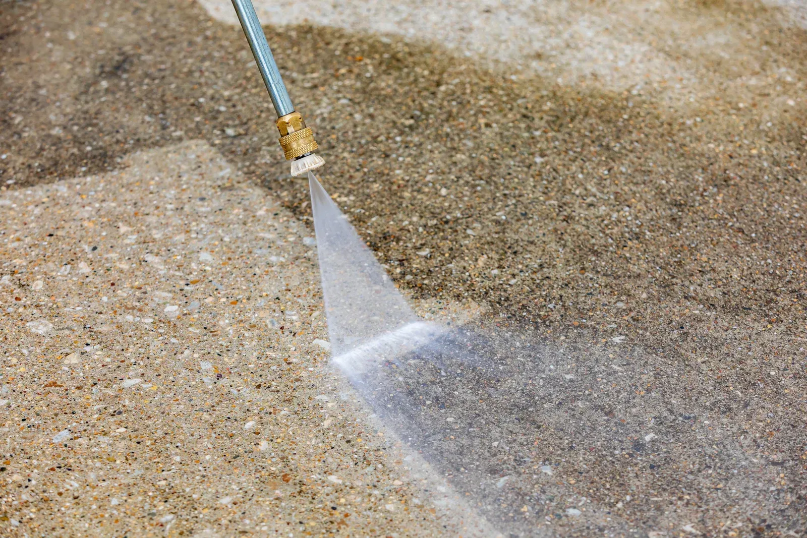 Pressure washer spraying water on a concrete surface, cleaning a path.