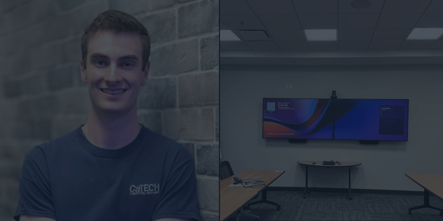 Smiling man in a dark T-shirt standing in a modern office with TV in background
