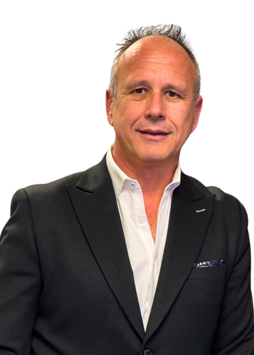 Man in black suit and white shirt smiles, studio shot.