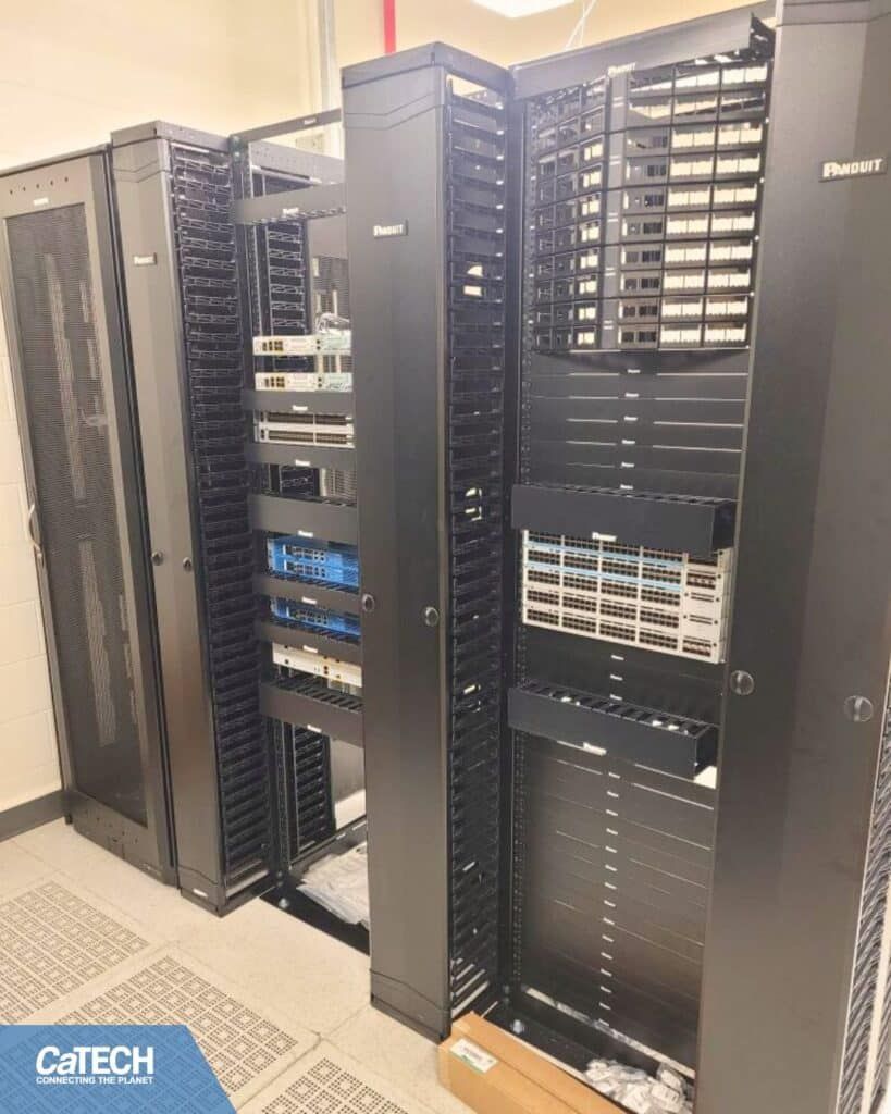 Three dark server racks, two with doors, inside a room, partially populated with equipment.