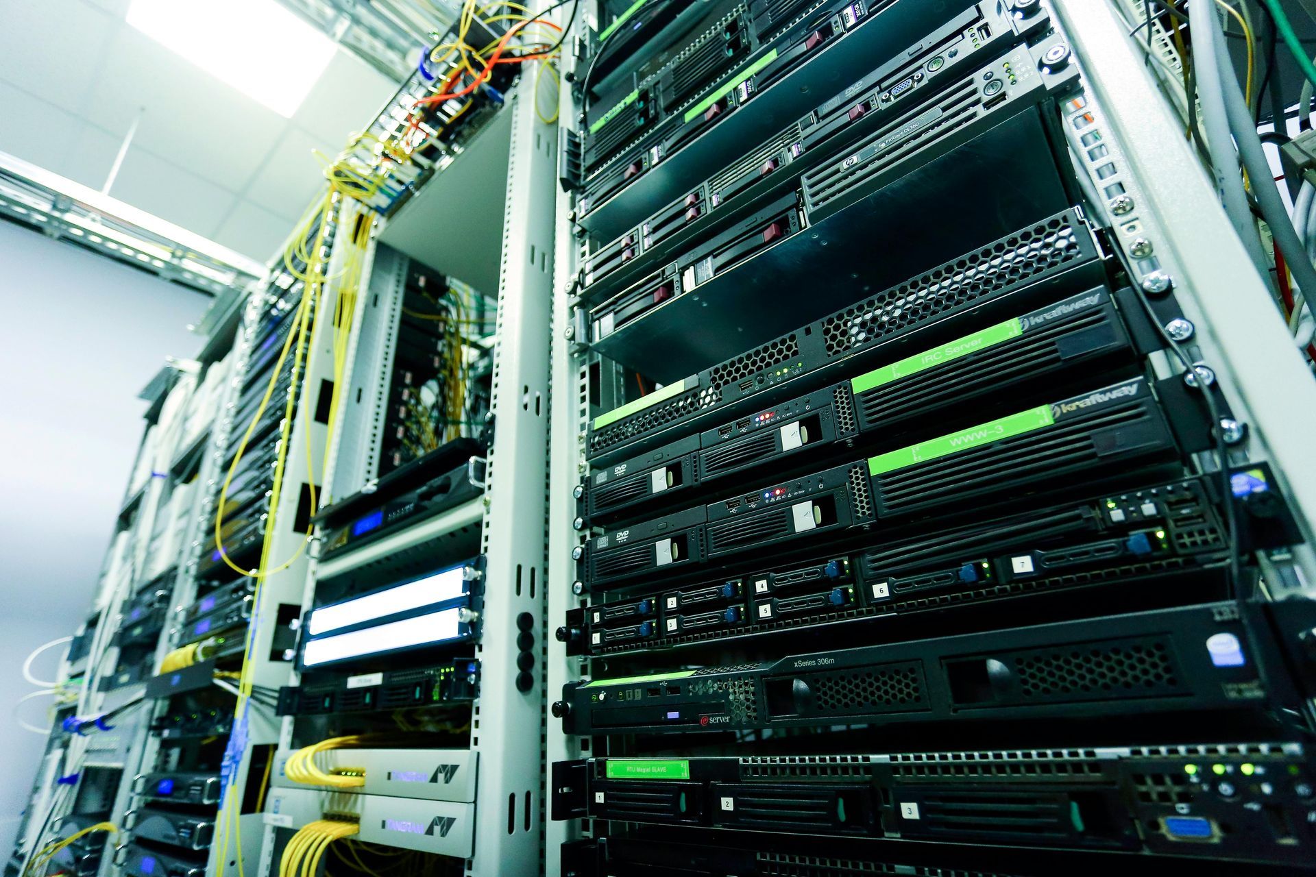 Rows of server racks in a bright data center with cables and blinking lights
