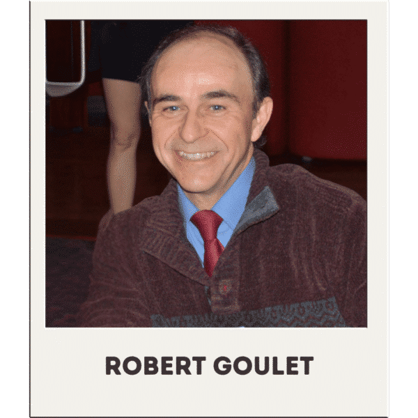 Robert Goulet in a burgundy sweater, blue shirt, and red tie, smiling.